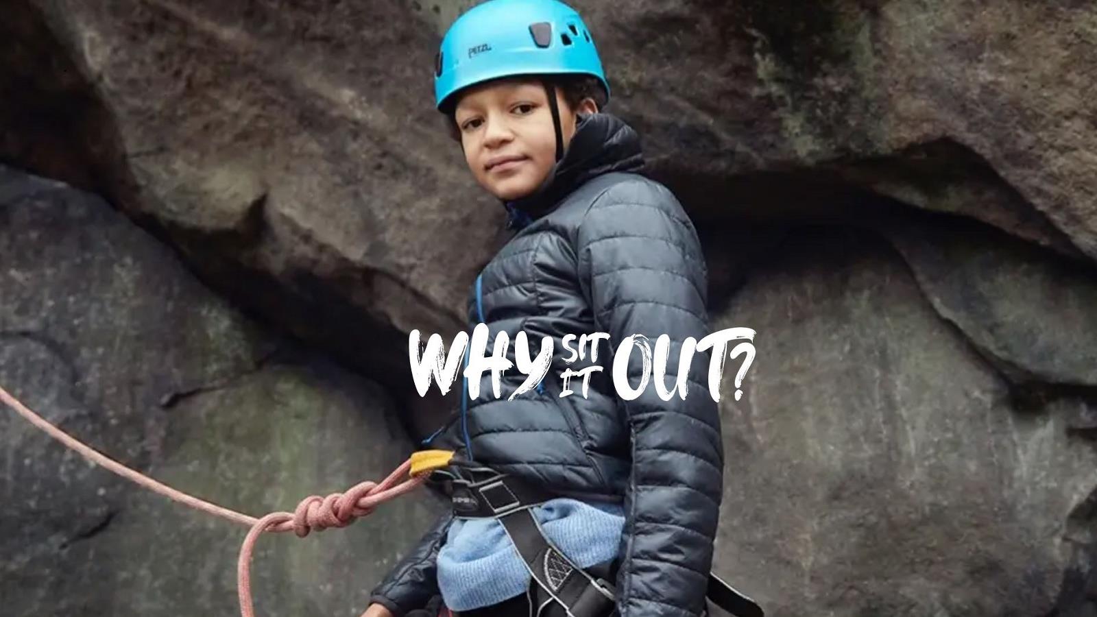 Boy in blue helmet climbing up rock face