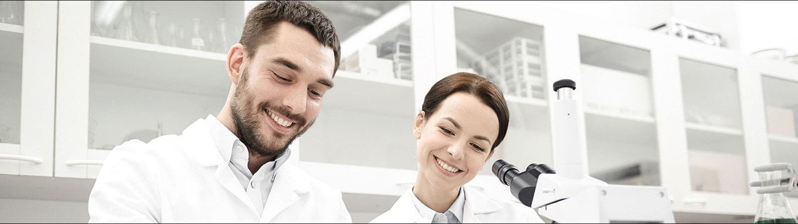 Male and female researchers in a lab taking notes